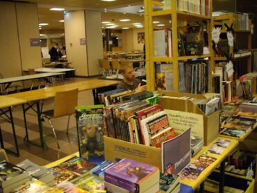 OctoGônes 2011. Le stand Temps-Livres, et celui de la librairie Omerveilles. Avec Fred en plein travail.